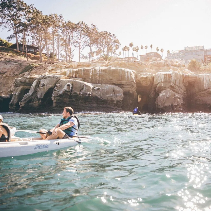 A guide leading beginners on a La Jolla canoe kayak tour into a sea cave in the La Jolla Ecological Reserve, San Diego, California