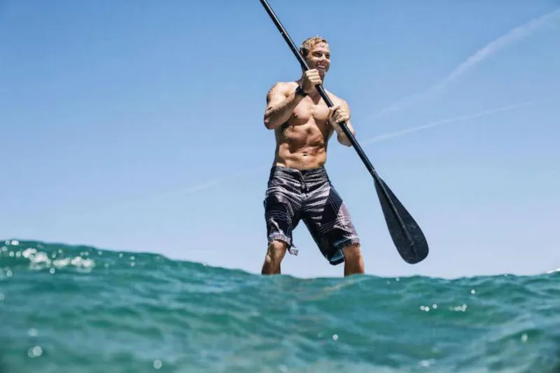 A paddler on a stand-up paddleboard over the kelp forest near the La Jolla sea caves, an alternative to a La Jolla canoe tour, San Diego